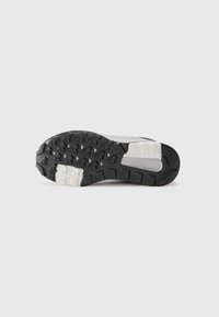Sport shoe sole featuring a textured black rubber bottom with a white midsole and a distinct tread pattern for traction.