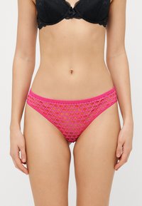 Rosafarbene Spitze-String-Unterwäsche mit einem ausgestanzten Kreismuster, elastischem Bund und glatter Textur, entworfen für Komfort und Passform.