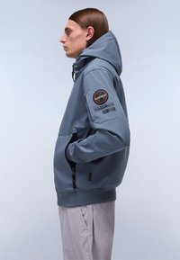 Kapuzensweatshirt in Hellgrau, aus weichem Stoff gefertigt. Verfügt über eine Reißverschlusstasche, gerippte Säume und Bündchen sowie ein Logo-Patch am Ärmels.