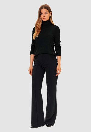 Maglione nero a collo alto e pantaloni neri su misura. Il maglione ha maniche lunghe e un design aderente. I pantaloni presentano una gamba dritta e un dettaglio di piega.