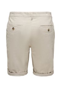 Short beige pour homme avec revers roulés, passants de ceinture et deux poches arrière fermées par des boutons.