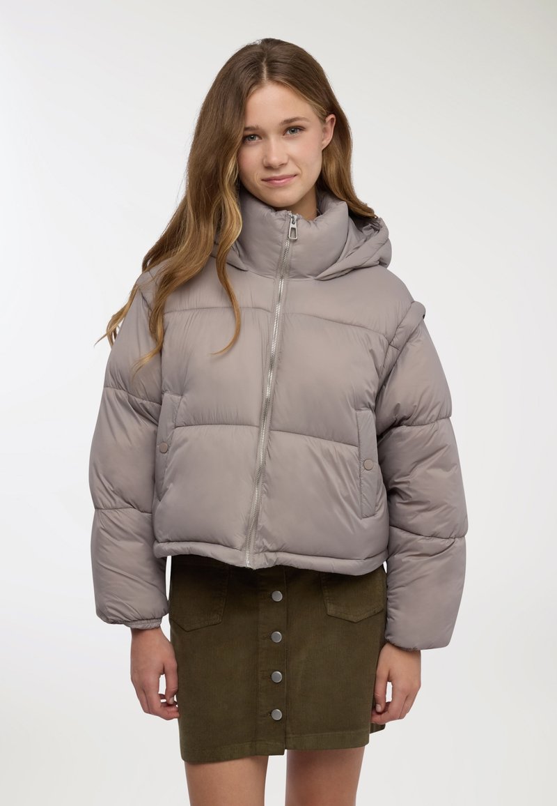 Giacca a piumino grigia con collo alto, cerniera frontale e design corto. Presenta una texture liscia e tasche laterali. Abbinata a una gonna in velluto a coste verde.