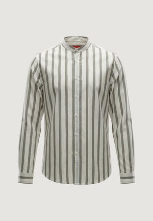 Camicia bianca a maniche lunghe con righe verticali nere, colletto alla coreana e chiusura con bottoni sul davanti su uno sfondo chiaro uniforme.