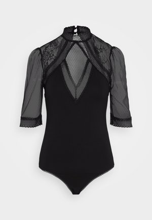 Svart bodysuit med høyt hals, gjennomsiktig mesh lange ermer, prikkete mønster og blondekant. Har en dyp V-halsutskjæring og trykknapplukking i bunn.