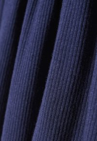 Marineblau gerippter Strickstoff, der mit verlängerten vertikalen Linien präsentiert wird und Textur sowie gleichmäßige Farbdarstellung hervorhebt.