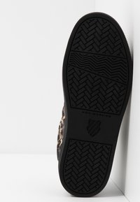 Tenisky s leopardím vzorem mají černou gumovou podrážku neznačící stopy, texturovaný vzor na podrážce a měkký svršek v odstínech béžové a hnědé.