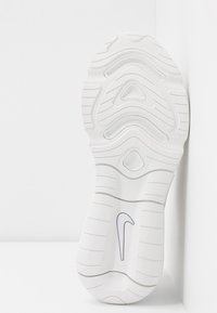 Semelle de sneaker blanche avec des rainures en relief, texture lisse et un logo swoosh bien visible en gris. Bords légèrement surélevés.