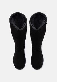 Μαύρες σουέτ μπότες μέχρι το γόνατο με μαλακή εσωτερική επένδυση, στρογγυλή μύτη και αντίθετη υφή στην κορυφή, με διακοσμητικά επενδυτικά κουμπιά στο πλάι.