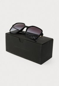 Fekete, téglalap alakú napszemüveg, fokozatos lencsékkel, egy fekete dobozon elhelyezve, amelyen az "Armani Exchange" felirat áll. Karcsú műanyag keret, fokozatosan keskenyedő karokkal.
