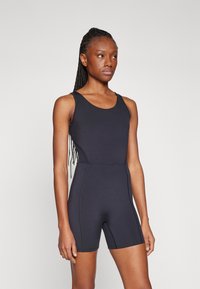 Černý elastický body s designem na tank top, s bezproblémovými stranami a přiléhavým střihem, který sahá do poloviny stehna. Hladká textura.