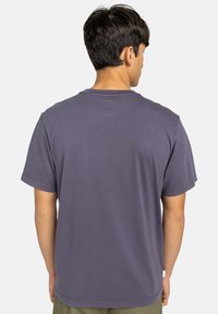 T-shirt a maniche corte in cotone di un profondo colore viola. Presenta un collo rotondo, una vestibilità rilassata e dettagli di cucitura minimi agli orli.