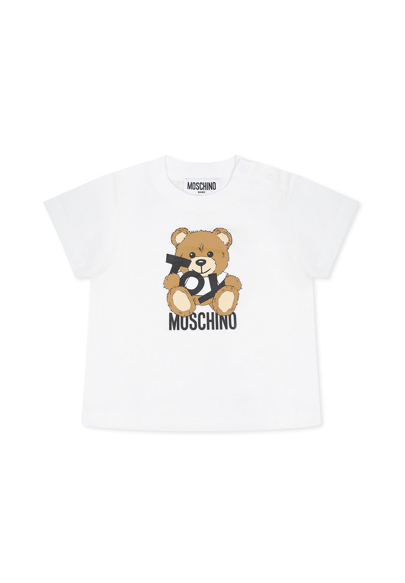 T-shirt bianca in cotone con grafica di un orso cartone animato e testo "TOY" in nero. Maniche corte e scollatura rotonda con chiusure a pressione.