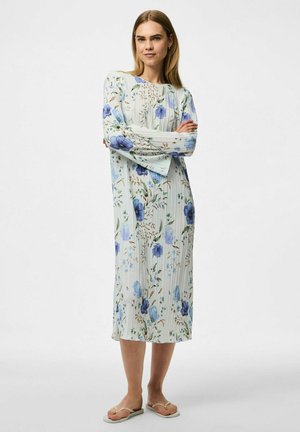 Vestido floral en azul claro y blanco, con un diseño plisado, mangas largas y un corte a la altura de la rodilla. Destacan flores azules y hojas verdes.