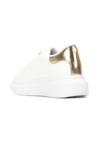 Zapatilla blanca con parte superior lisa, que presenta un detalle metálico dorado en el talón y una suela gruesa blanca. La parte trasera texturizada ofrece agarre.