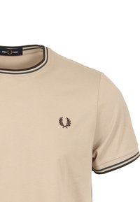T-shirt beige a maniche corte con scollo rotondo, collo a coste con strisce verdi e marroni, e un piccolo logo ricamato sul petto.