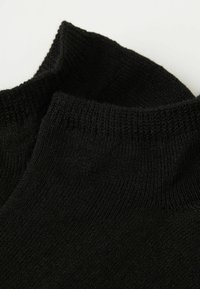 Sort strikket rullekrave med en tekstureret overflade, der har ribbede kanter og en glat inderside. Materialet virker blødt og fleksibelt.