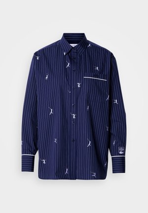 Camisa azul marino con botones y rayas blancas, adornada con figuras bordadas y divertidas. Cuenta con un bolsillo parche y ribete blanco a contraste en los puños.