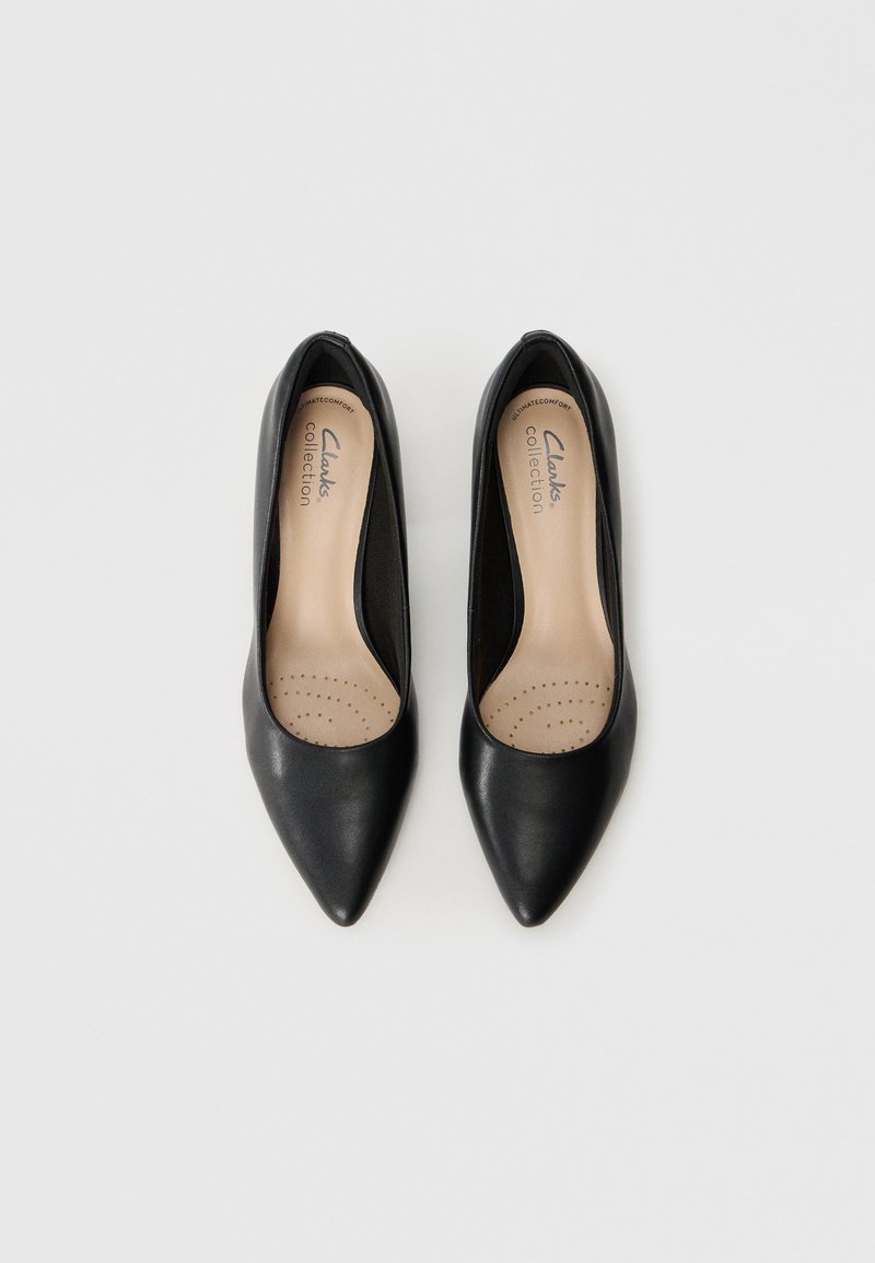 Chaussures noires en cuir à bout pointu avec une finition lisse, dotées d'une semelle intérieure rembourrée et d'un design minimaliste. Logo visible à l'intérieur.