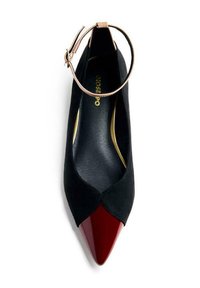 Chaussure à talon haute en suède noir avec un bout pointu en vernis rouge et une lanière à la cheville. L'intérieur présente un logo doré sur une semelle noire.
