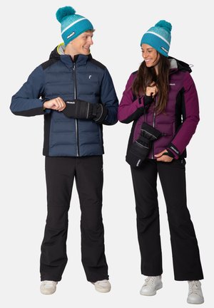 Two individuals wear outerwear: a navy blue puffer jacket and a purple insulated jacket. Both have black ski pants and matching mittens.
