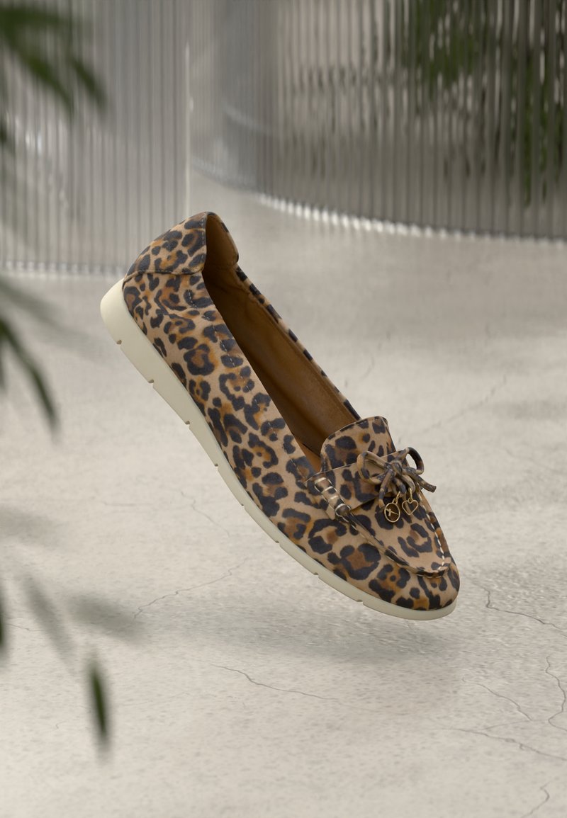 Chaussure à enfiler à motif léopard avec une tige douce, une semelle plate blanche et un nœud décoratif avec des accents en métal doré.