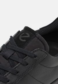 Sneaker nera con una parte superiore in pelle liscia, dettagli in suede testurizzato e lacci piatti, colletto imbottito e linguetta in rete traspirante.