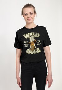 T-shirt nera con un design grafico che presenta il testo "WILD ONE" e un'illustrazione di un personaggio con un cappello, insieme ai dettagli di un club motociclistico.