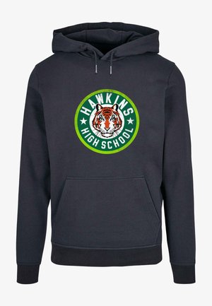 Donkerblauwe hoodie met frontale kangaroo zak. Heeft een circulaire afbeelding met een tijger en de tekst "HAWKINS HIGH SCHOOL" in groen en wit.
