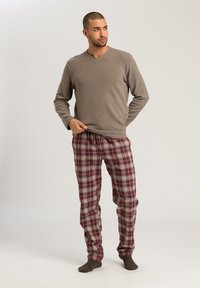 Grijze lange mouwen V-hals top gecombineerd met bordeauxrode en crèmekleurige geruite broek met een elastische tailleband, een ontspannen pasvorm en geribbelde boorden.