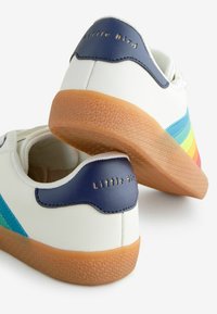 Baskets en cuir blanc avec des accents bleus, présentant un design de rayures arc-en-ciel et une semelle en caoutchouc texturé couleur gomme. "Little Bird" embossé en doré sur le talon.