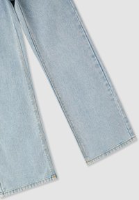 Jasnoniebieskie dżinsy o prostym kroju, z widocznym przeszyciem i gładką teksturą. Cięte na standardową długość, bez ozdób.