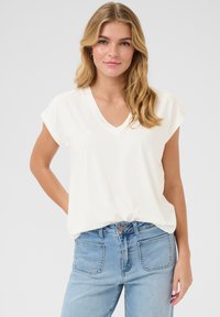 Witte blouse met V-hals en korte mouwen, van zacht materiaal, met een losse pasvorm, gedragen met lichtblauwe high-waisted jeans met achterzakken.