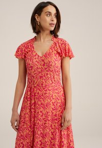 Pink and orange floral-patterned dress with ruffled sleeves, V-neckline, and a tied waist, made from lightweight fabric.