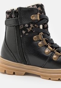 Sorte skinn ankle boots med blomstermønster på overflaten, gyldne detaljer, teksturert gummisåle og glidelås på siden for enkel påkledning.