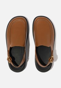 Bruine leren loafers met een gladde textuur, voorzien van een verstelbare gouden gesp en een zwarte rubberen zool.