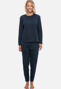 Mörkblå långärmad tröja och matchande joggerbyxor i ett mjukt, elastiskt tyg. Byxorna har elastiska muddar och en avslappnad passform.