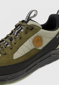 Olivgrüne und schwarze Sneaker mit Obermaterial aus Wildleder und Textil, runder Zehenform, Schnürdesign und gestickten Akzenten. Verfügt über ein rundes Logopatch.