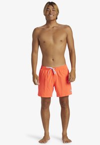Bañadores de un brillante color naranja con cintura ajustable, bolsillos laterales y un pequeño parche de logo. Fabricados con material ligero y de secado rápido.