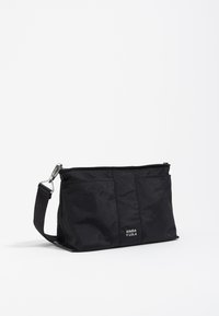 Clutch bag nera in nylon con chiusura a zip, dotata di tracolla staccabile e un'etichetta del logo. Texture liscia con design minimalista.