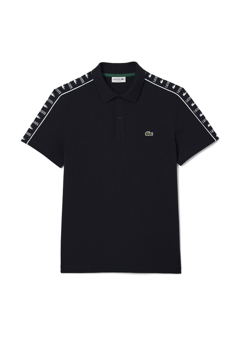 Camisa polo negra de algodón con cuello clásico, que presenta cinta de marca blanca en los hombros y un pequeño logo de cocodrilo verde.