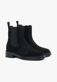 Czarne zamszowe botki Chelsea z elastycznymi panelami bocznymi i pętelkami do łatwego zakładania. Solidna czarna gumowa podeszwa, zaokrąglony nosek i elegancki design.