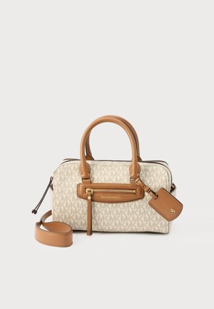 Μπεζ τσάντα χειρός Michael Kors με μονόγραμμα, καφέ δερμάτινες λαβές, μπροστινή τσέπη με φερμουάρ, αποσπώμενο λουράκι και δερμάτινη ταμπέλα σε λευκό φόντο.