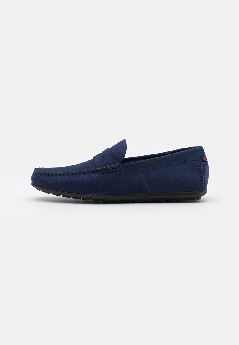 Mocassins en daim bleu marine avec des détails piqués, profil bas, semelle en caoutchouc et design à enfiler. Lignes épurées et accents minimalistes.