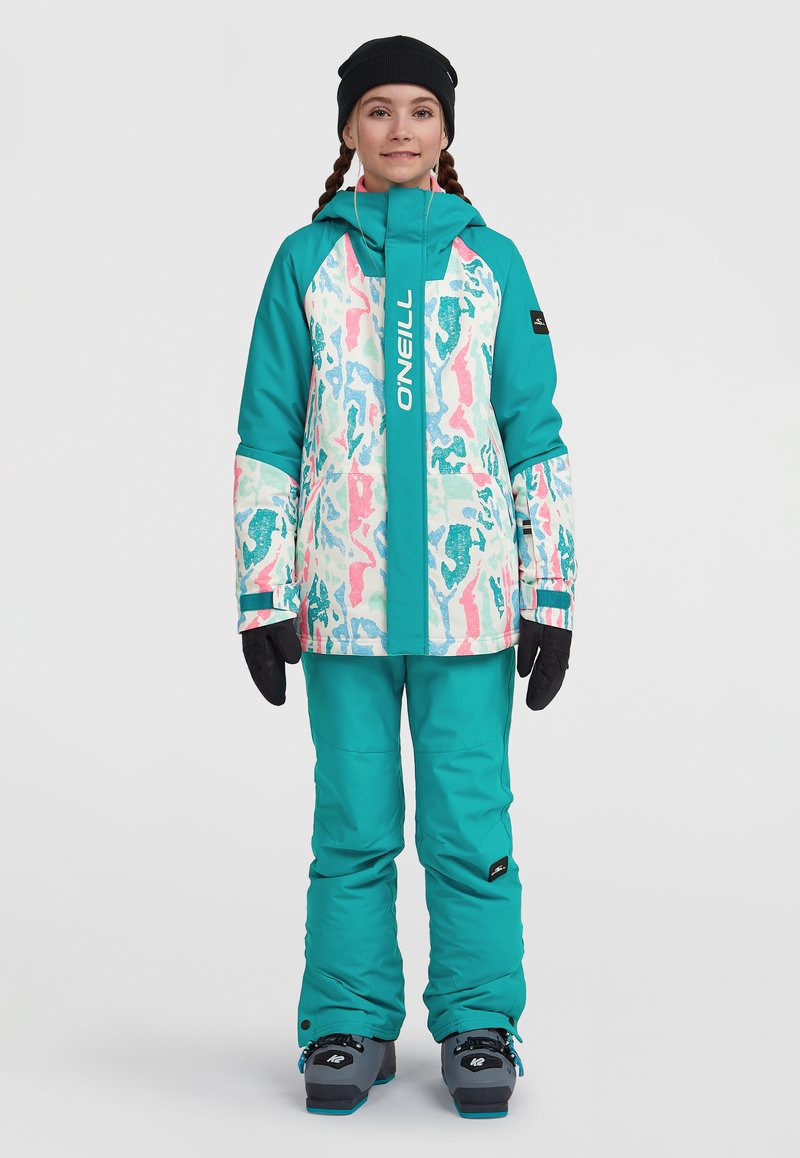 Turkis skijakke med et farverigt, abstrakt print og en frontlynlås, parret med matchende bukser. Sorte handsker og en hue fuldender outfittet.