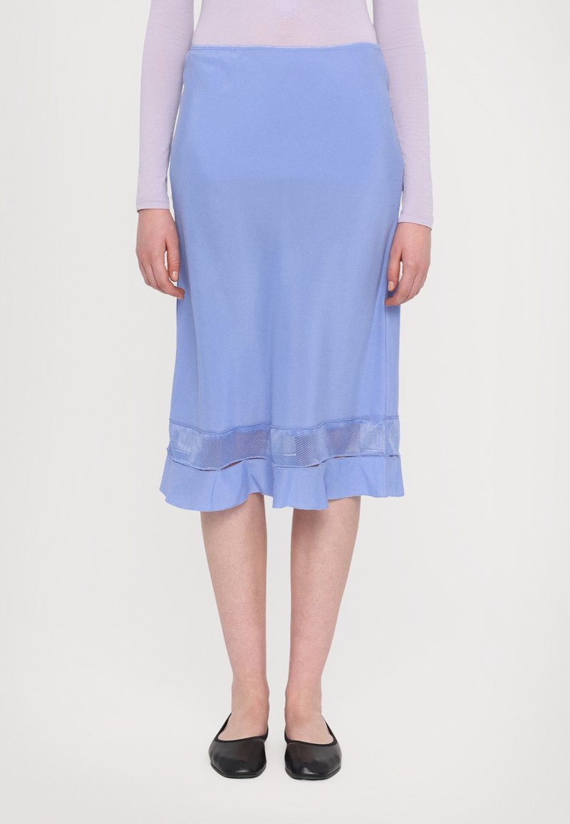Blauwe midi-rok met een soepele textuur, gerimpelde zoom en een transparante mesh-laag aan de onderkant, gecombineerd met zwarte platte schoenen.