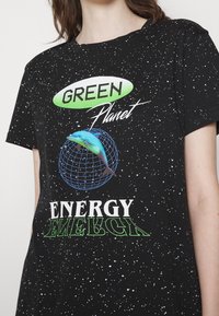 T-shirt noir avec un graphisme sur le thème de l'espace affichant le texte "GREEN Planet", un dauphin sur un globe en grille, et "ENERGY" en dessous en vert et blanc.