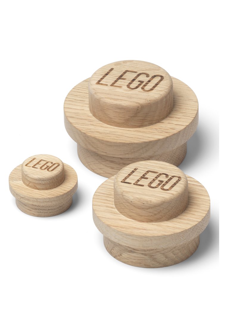 Drie houten LEGO-achtige pennen in verschillende maten, met gegraveerd "LEGO" bovenop, met gladde oppervlakken en afgeronde hoeken. Lichte houtkleur.