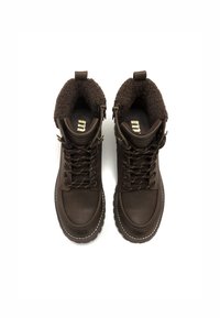 Botas marrones impermeables con un collar de piel sintética, cuentan con ojales de metal, cordones marrones y una suela de goma texturizada. El interior tiene una plantilla con logo.
