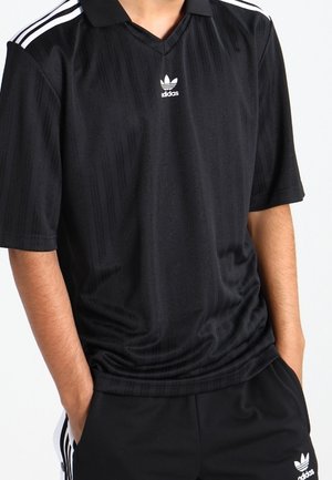 Schwarzes Adidas-Polohemd mit V-Ausschnitt, das dezente vertikale Streifenmuster und weiße Drei-Streifen-Akzente an den Schultern aufweist.