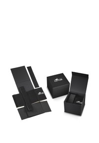 Conjunto de embalaje negro con diseño de caja plegable, acabado texturizado y un logotipo en contraste en la parte frontal, junto a elementos aplanados para el cierre.